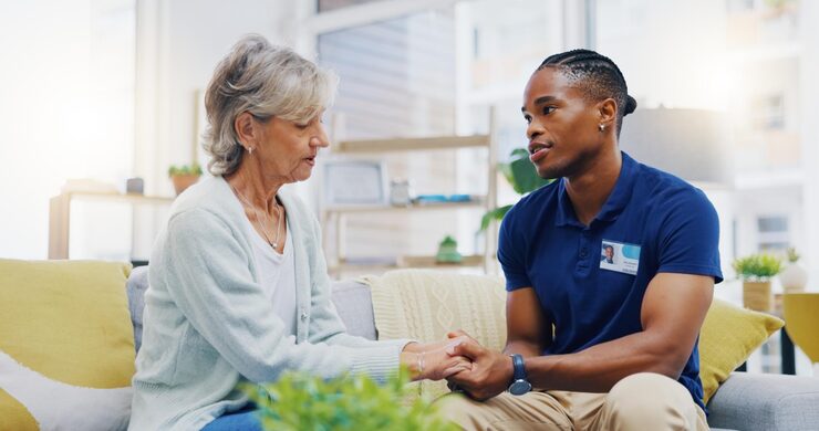 Caregiver in navy scrubs sitting with an older adult in a bright living room in Cleveland
